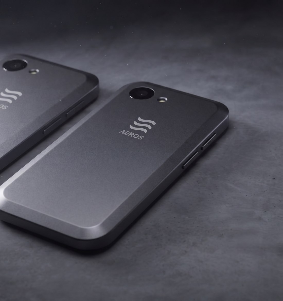 Two AEROS Centi concept phones lying face down on a concrete surface, the AEROS mark on each back