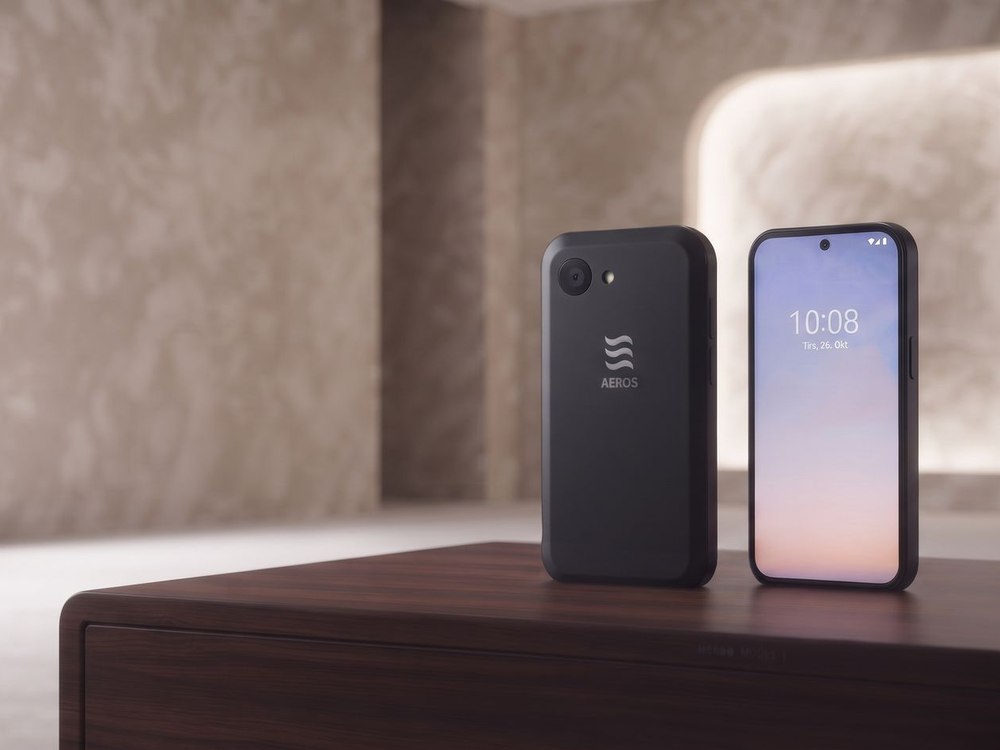 The concept phone shown front and back on a walnut surface in a warm, quiet room